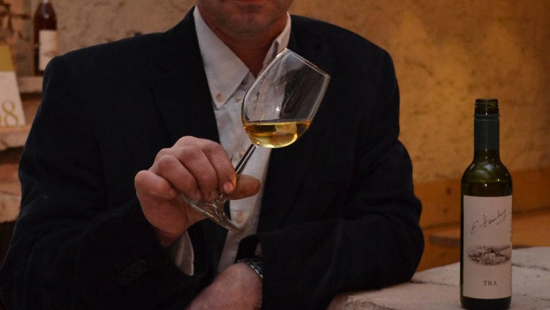 Heimburg Erich, © Heimburg Erich Mann mit Weinglas und Weinflasche in einem Weinkeller.