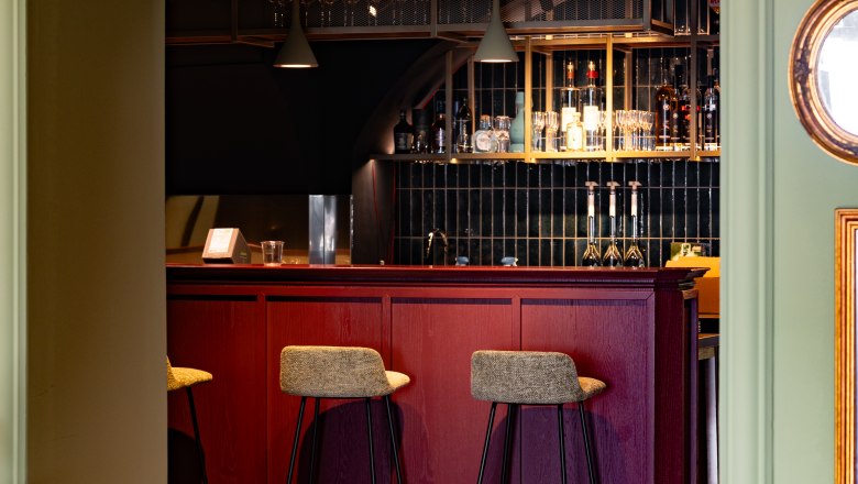 Elegante Bar mit roten Holzm&ouml;beln und hohen St&uuml;hlen.