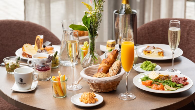 Ein gedeckter Frühstückstisch mit verschiedenen Speisen, Getränken und Blumen.