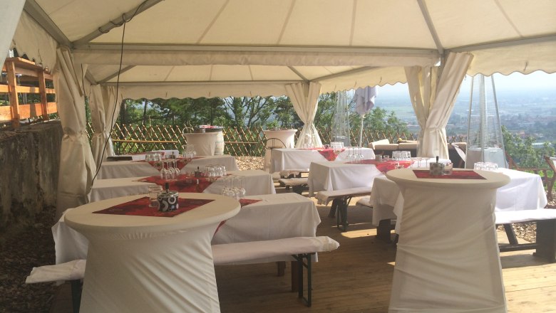 Festzelt mit gedeckten Tischen und Stehtischen, dekoriert f&uuml;r eine Feier.