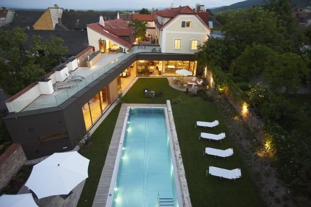 Luftaufnahme eines modernen Hauses mit Pool und Garten bei Abenddämmerung.